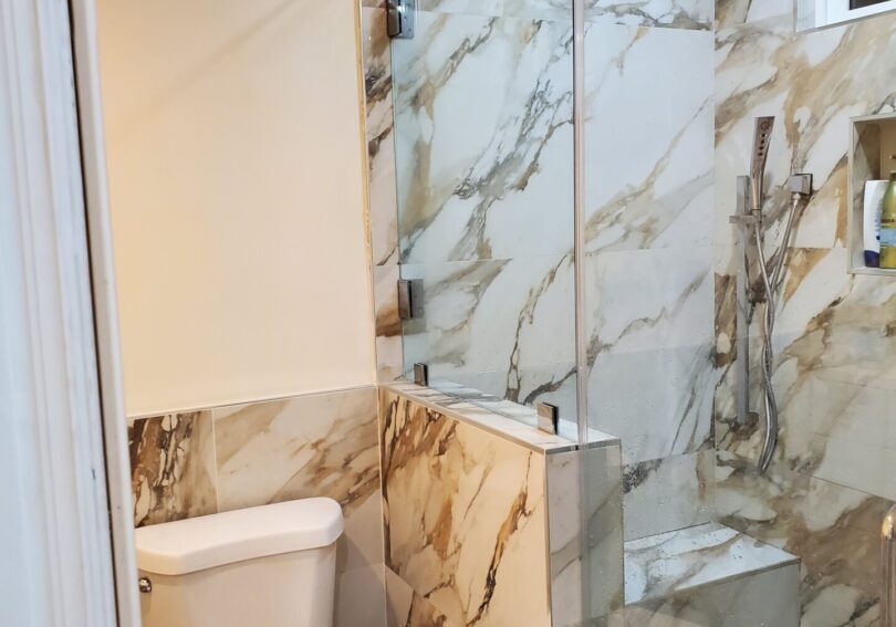 A bathroom with marble walls and floors, toilet and shower.